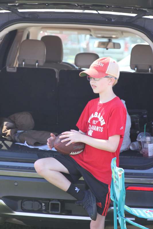 a boy sitting in the back of a car holding a football