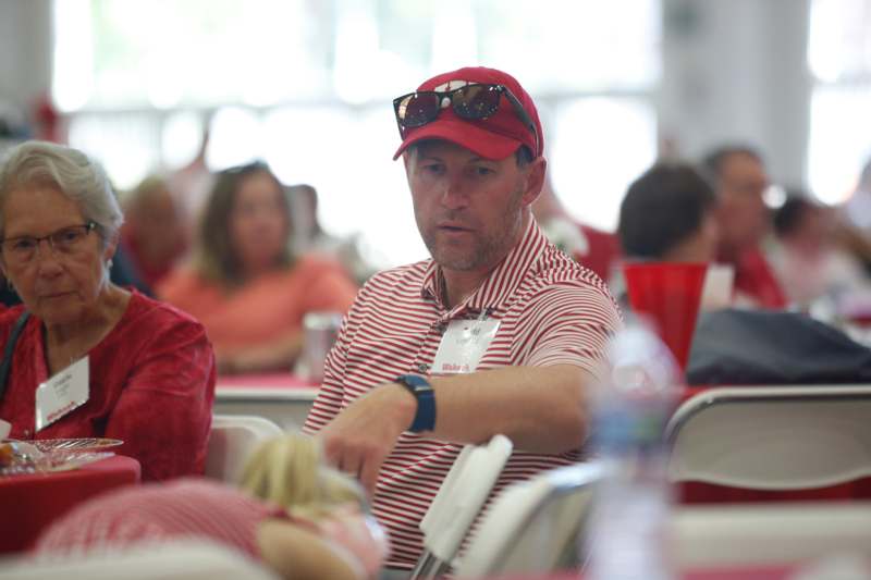 a man wearing a red hat and sunglasses sitting at a table