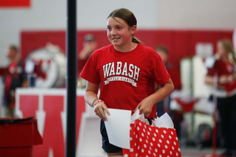 a girl in a red shirt holding a bag