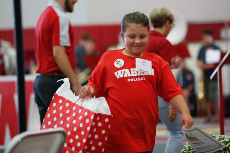 a girl in a red shirt holding a red and white polka dot bag