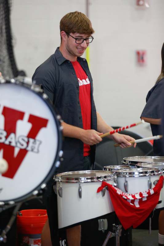 a man playing drums with a red and white stick