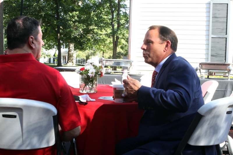 a man in a suit and tie sitting at a table with coffee cups