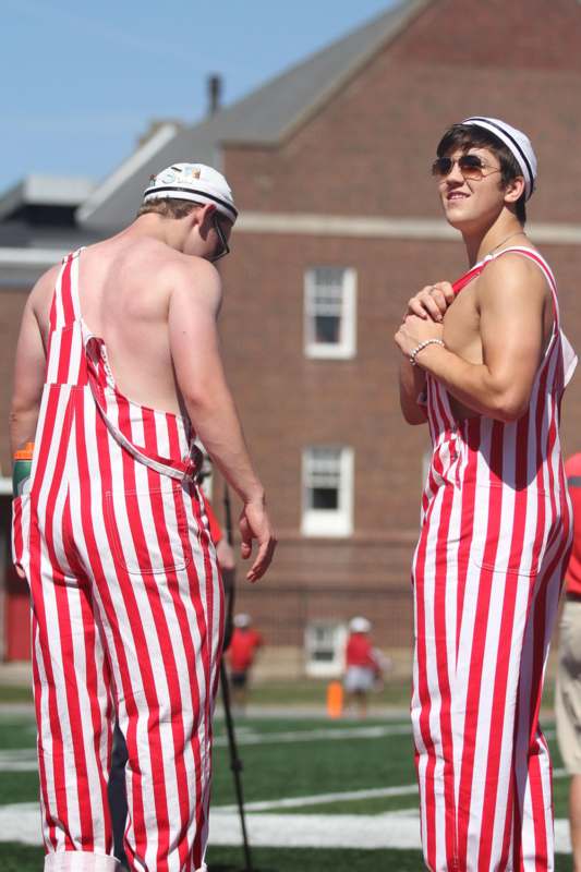 two men wearing striped overalls and hats