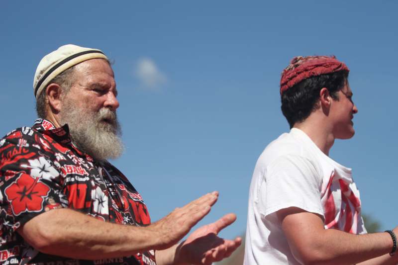 a man with a beard and a white hat with his hands out