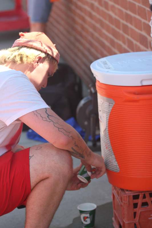 a man squatting down to put a cup on a water cooler