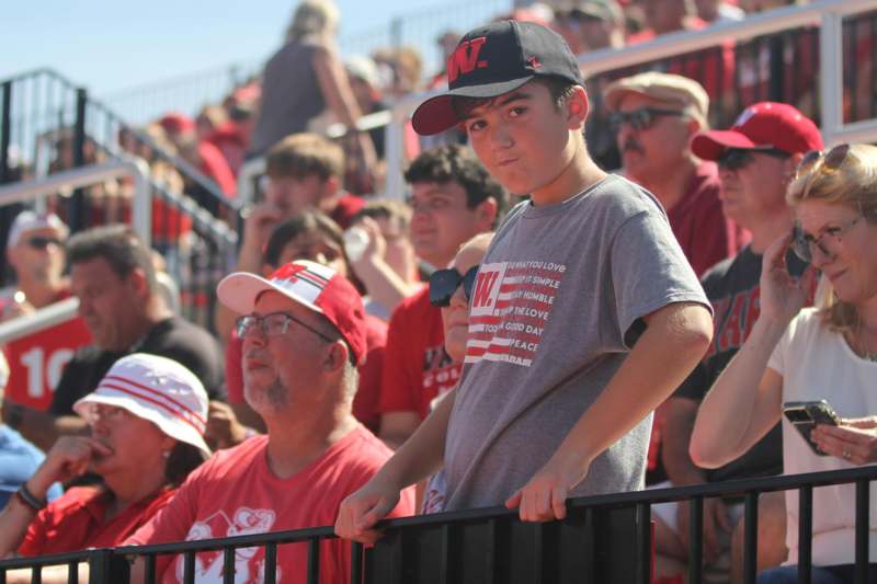 a boy leaning on a fence in a crowd