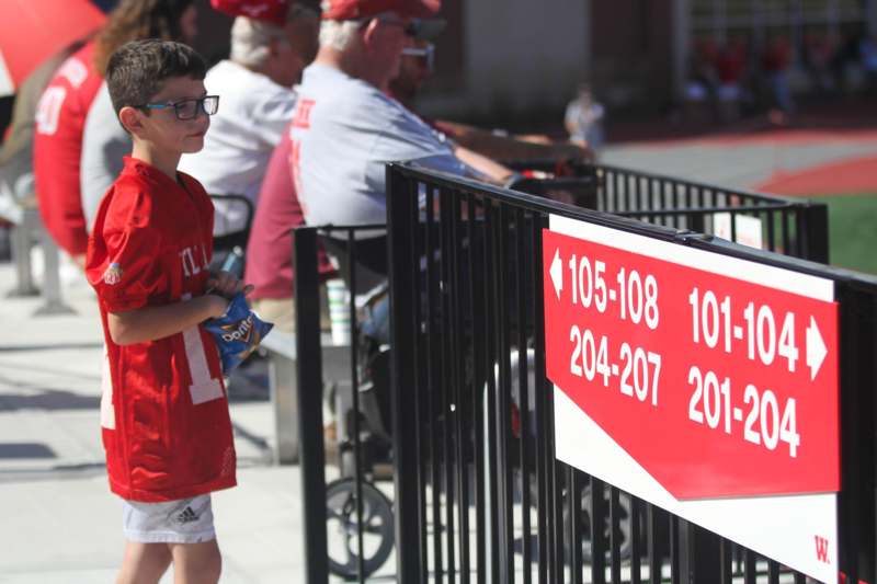 a boy standing in front of a fence with a sign