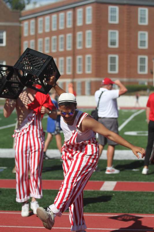 a man in striped overalls holding crates on a football field