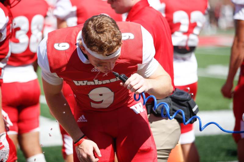 a man in a football uniform drinking from a hose