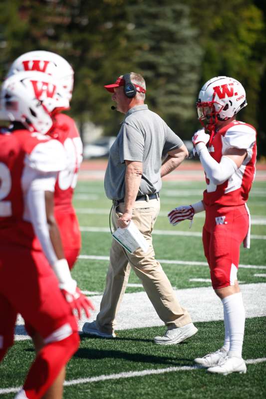 a football coach walking on a field with players