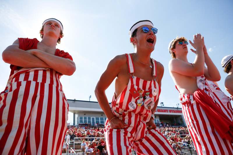 a group of men wearing striped overalls and standing in a crowd