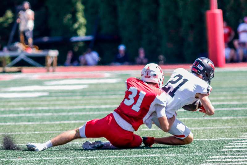 a football player falling down to catch another football