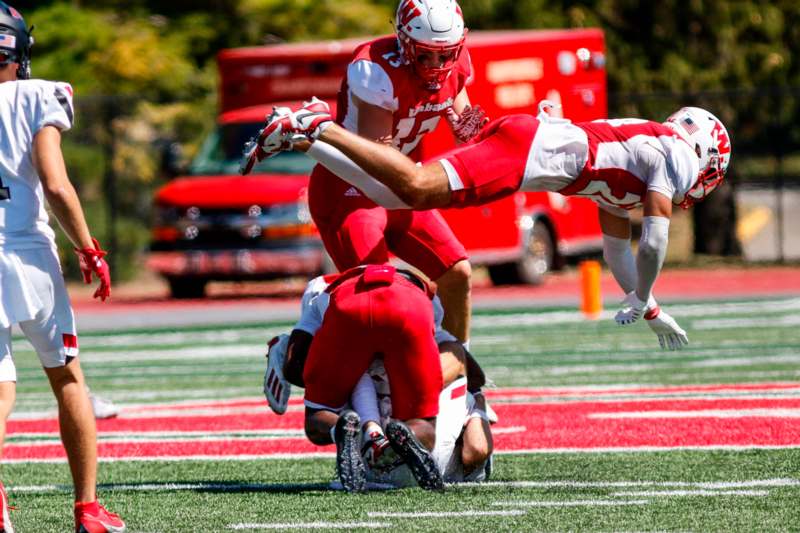 a football player falling over another football player