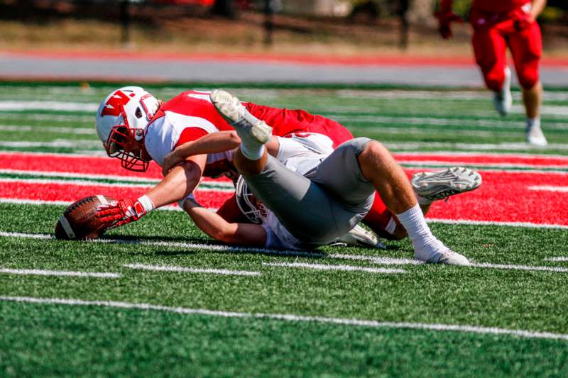 a football player falling over another football player