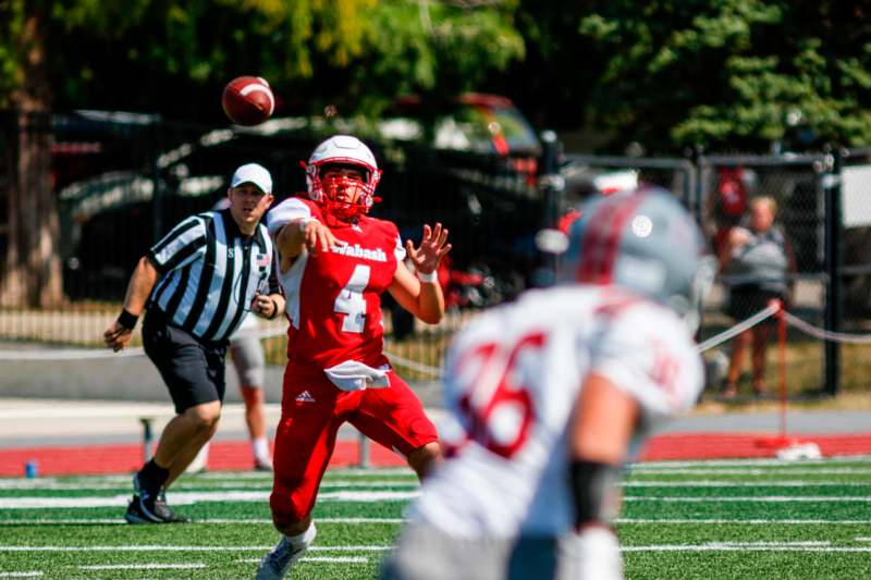 a football player in a red uniform throwing a football