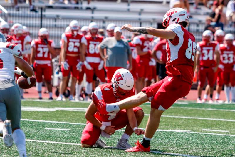 a football player kicking another football player on the ground