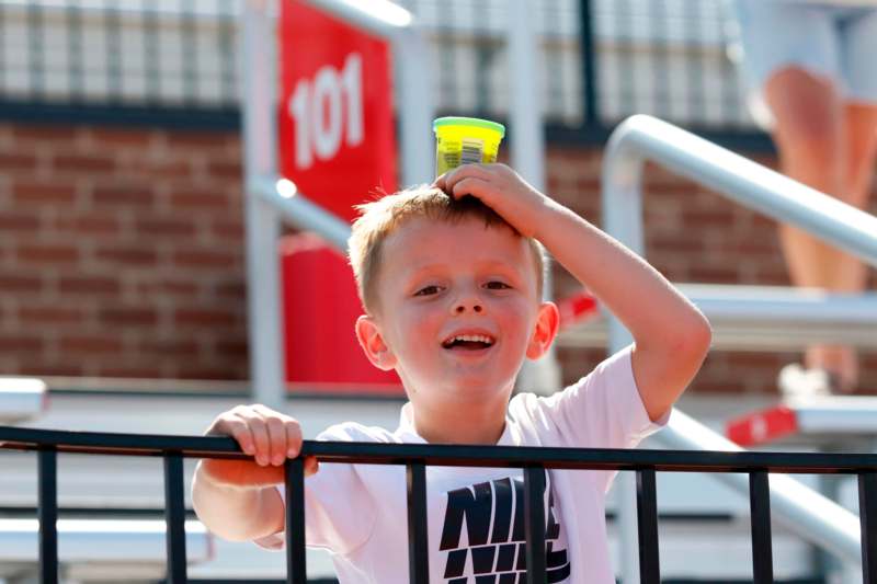 a boy holding a small cup on his head