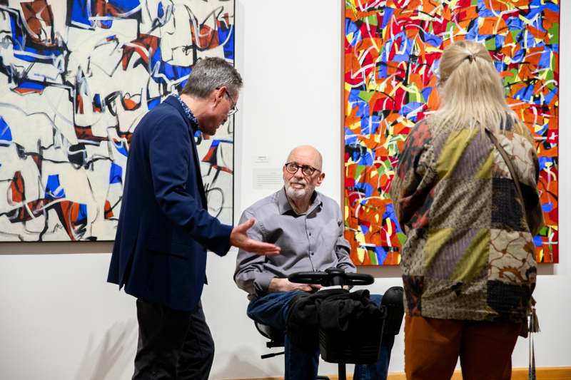 a group of people standing in front of a painting