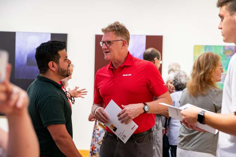 a man in a red shirt talking to a group of people