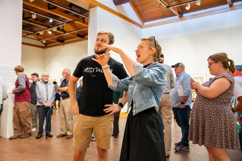 a man and woman in a room with people in the background