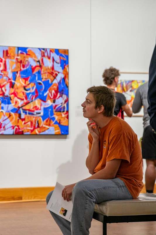 a man sitting on a wood floor looking at a painting