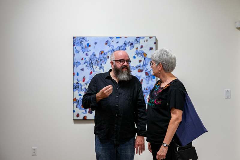 a man and woman standing in front of a painting