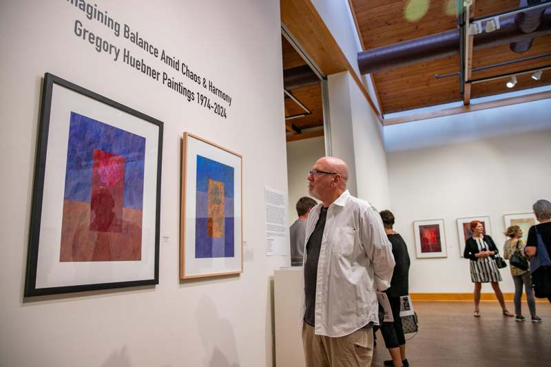 a man looking at a painting on a wall