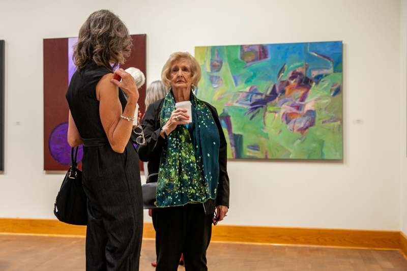 a group of women in a room with paintings