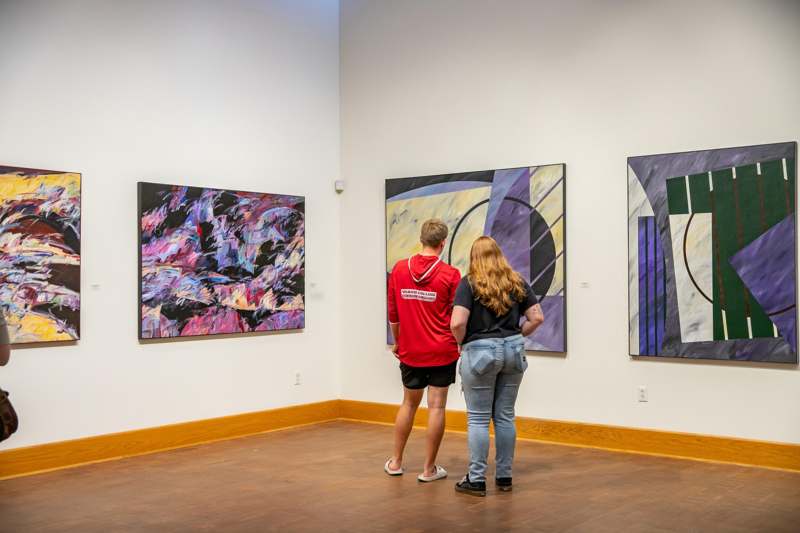 a man and woman looking at art on the wall