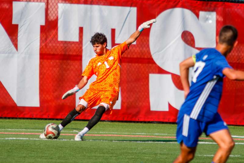 a man in an orange uniform kicking a football ball