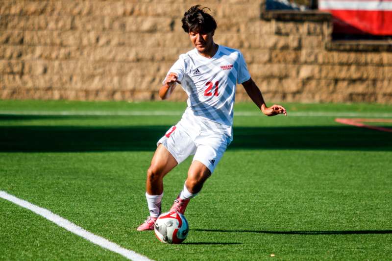 a man in a white uniform kicking a football ball