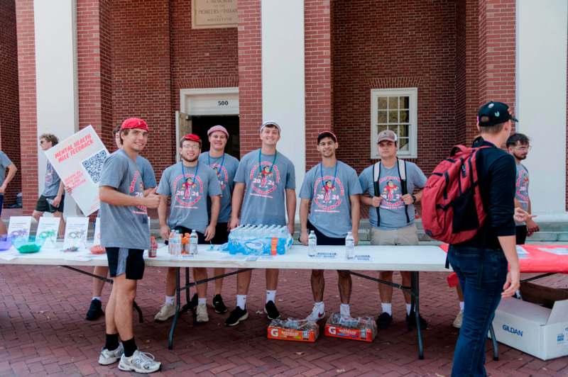 a group of men standing next to a table with water bottles