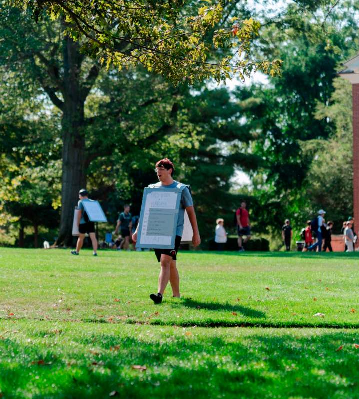 a man holding a sign in a grassy field