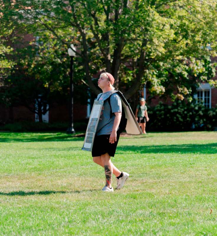 a man walking on grass with a cardboard box