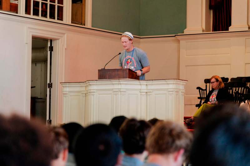 a man standing at a podium with a microphone in front of a crowd