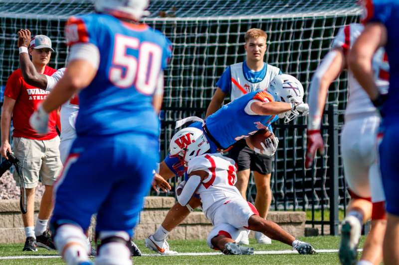 a football player falling over another football player