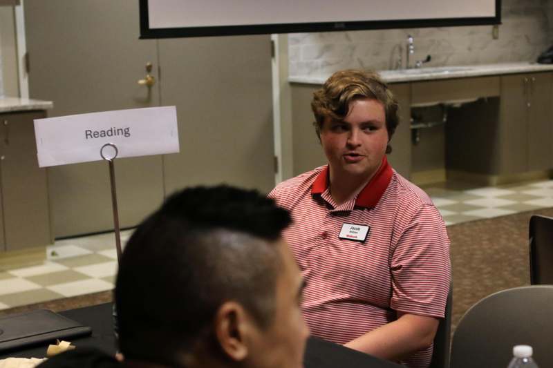 a man sitting at a table talking to another man