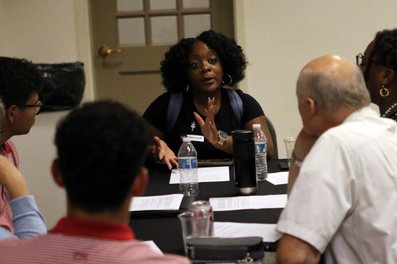 a woman sitting at a table with other people around it