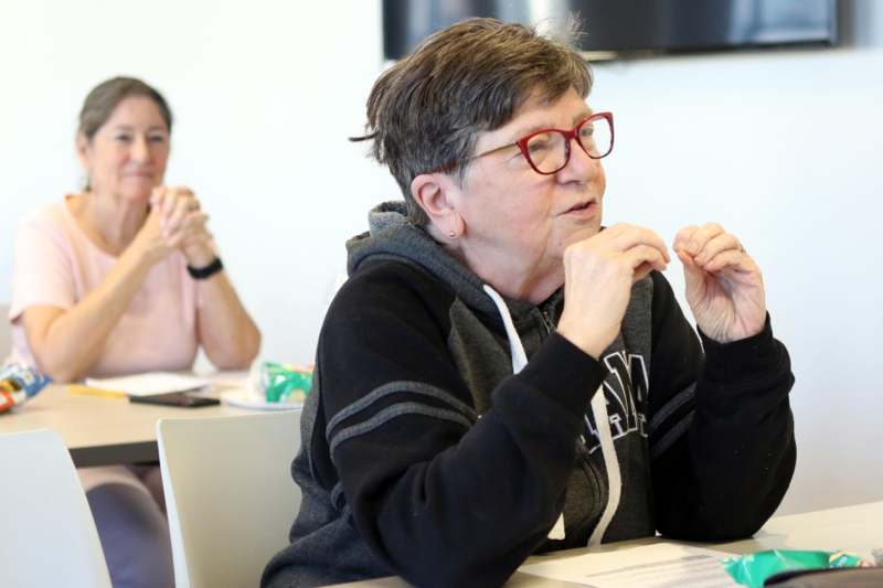 a woman sitting at a table with her hands clasped