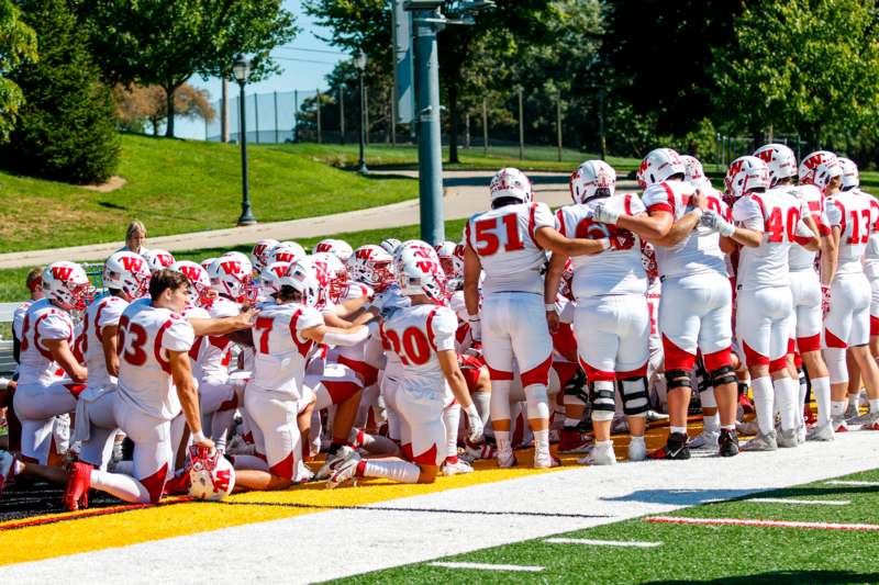 a group of football players huddle on a field