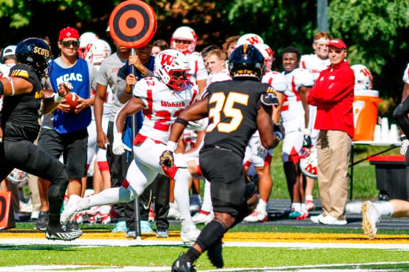 a football player running with a red and black frisbee