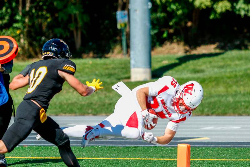 a football player in a uniform running with another football player in the air