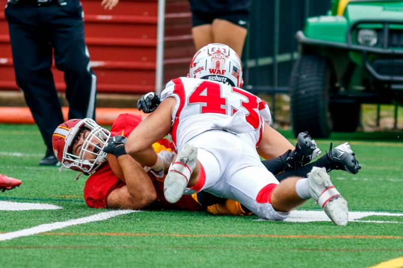 a football player falling over another player