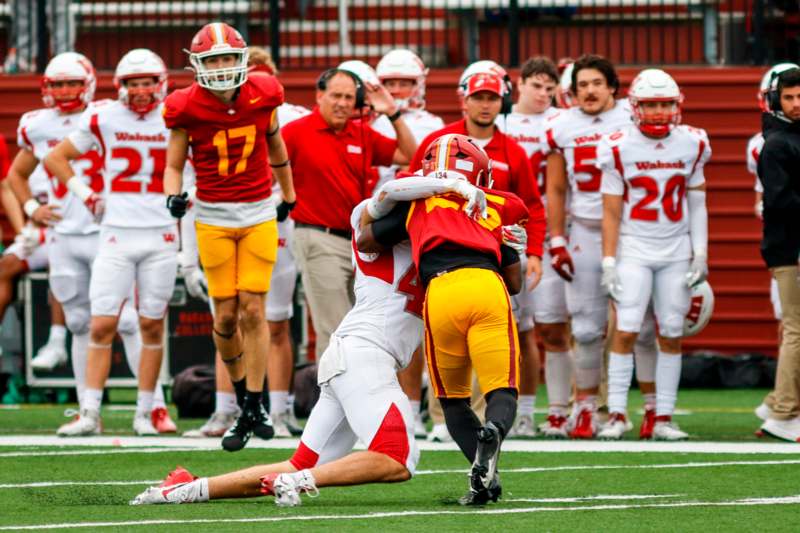 a football player in a red uniform holding another football player in a red uniform