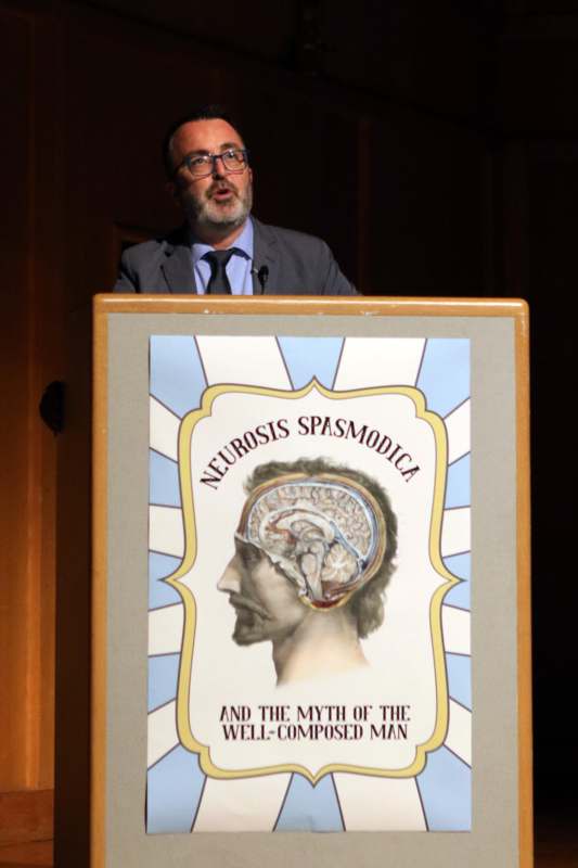 a man standing at a podium with a poster on it