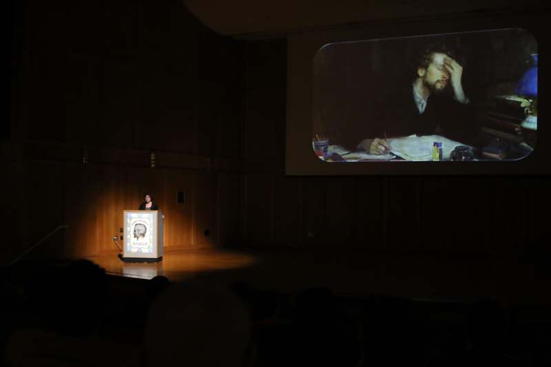 a woman standing at a podium with a projection screen