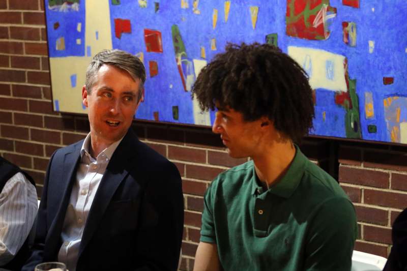 a man in a suit talking to a man in a green shirt