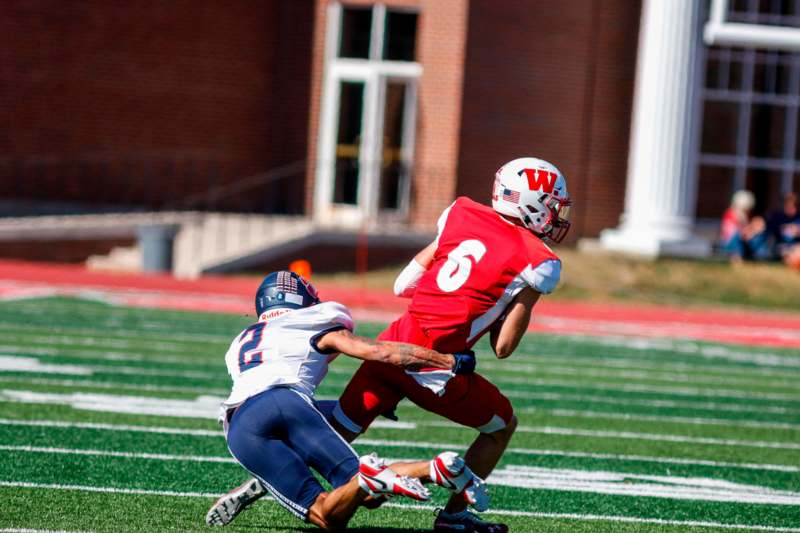 a football player in a red uniform running with another player in the back