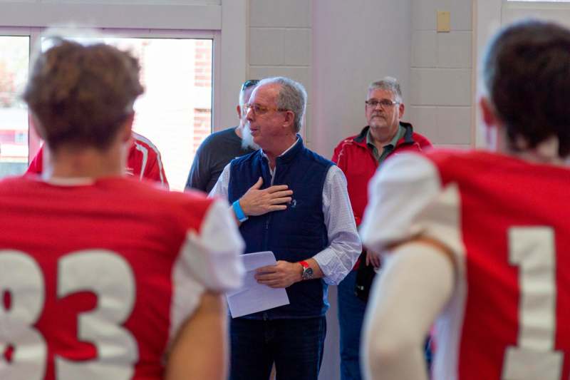 a man in a red vest talking to a group of people