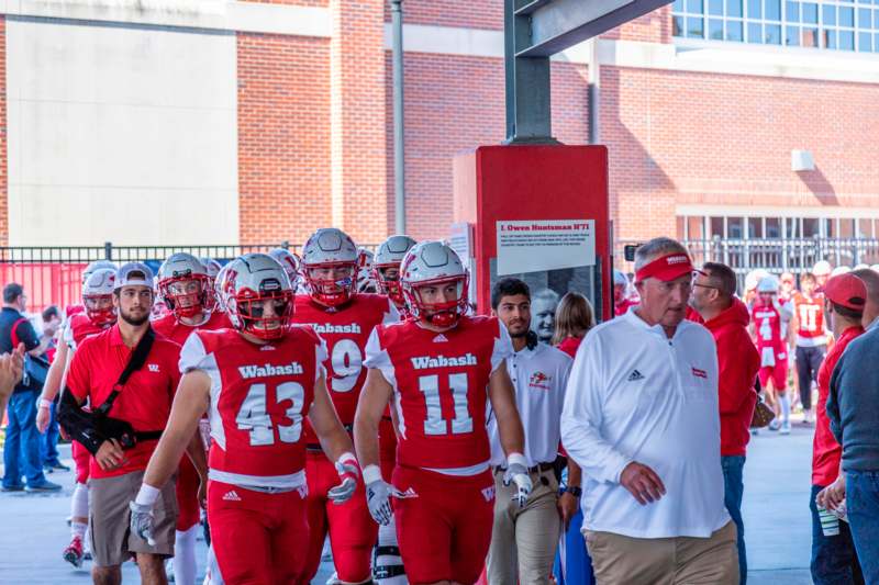 a group of football players walking down a sidewalk